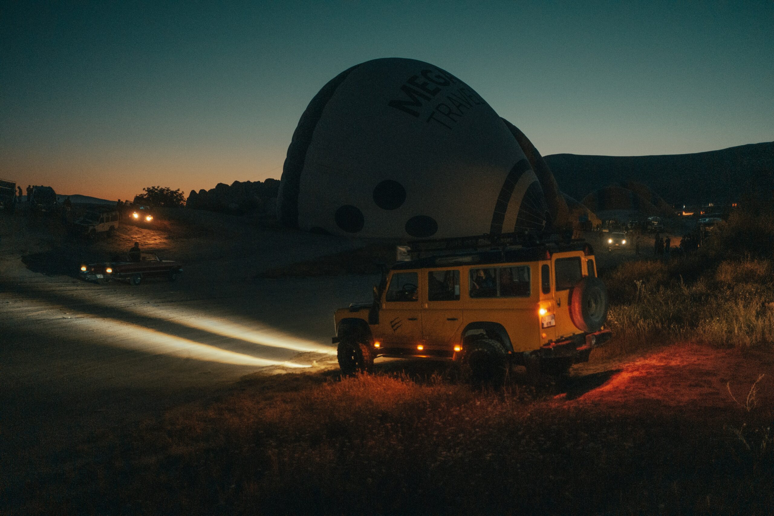 Yellow Jeep with its headlights on at dusk