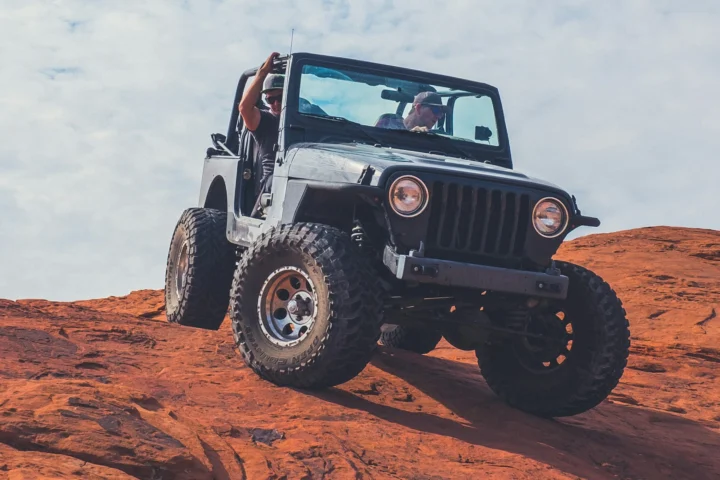 Jeep Wrangler with its doors off climbing red slickrock