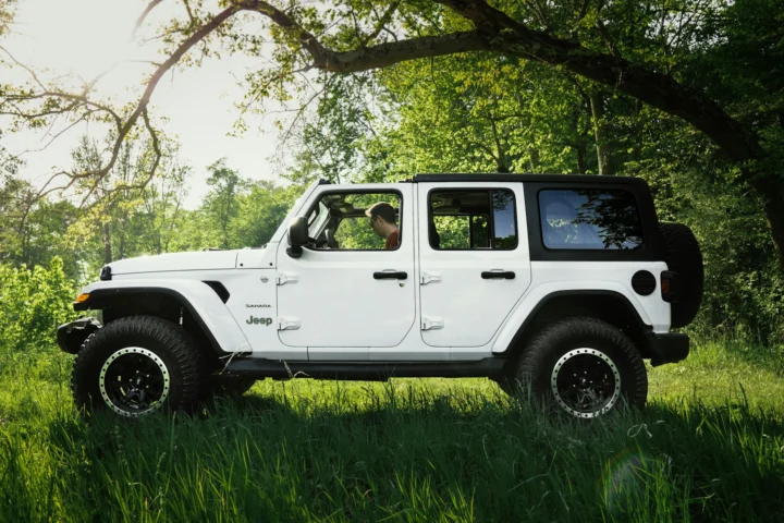 White Jeep Wrangler Unlimited parked on grass under a tree