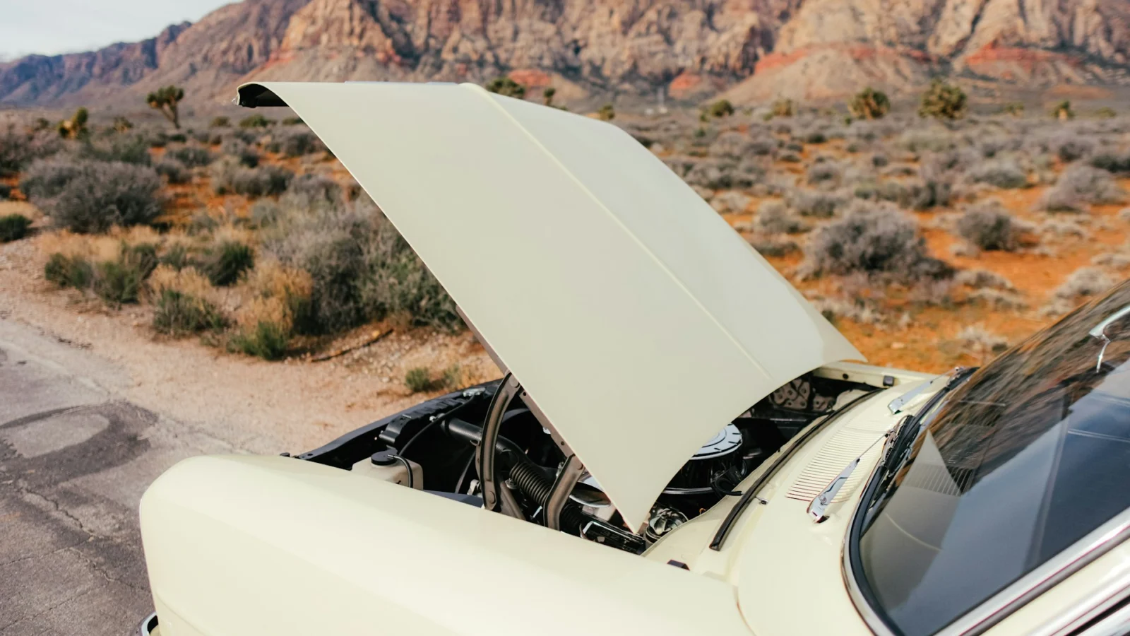 Car with its hood open on a desert road