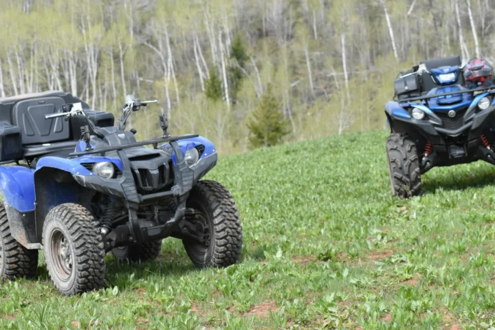 Two blue Yamaha utility ATVs parked in a grassy field